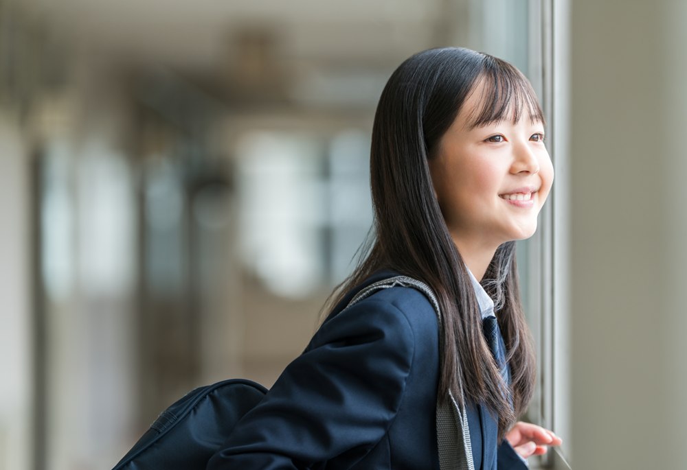 窓の外を眺める制服姿の生徒